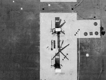 Aerial black-and-white fine art photograph of a remote Tuscan gas station, reduced to surface, line and shadow.